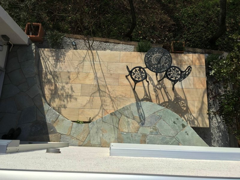 Stone Veneer Bench and Tile Terrace Surrounded by a Flowerbed