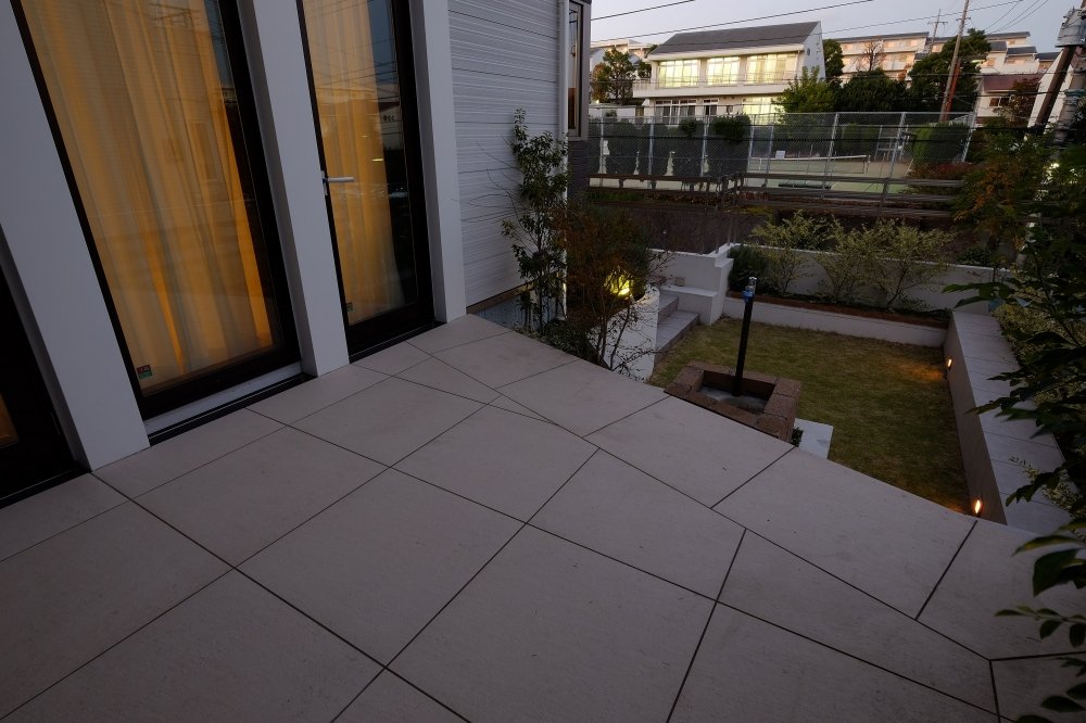 部屋の明かりが漏れ、夜も楽しめるタイルテラス
