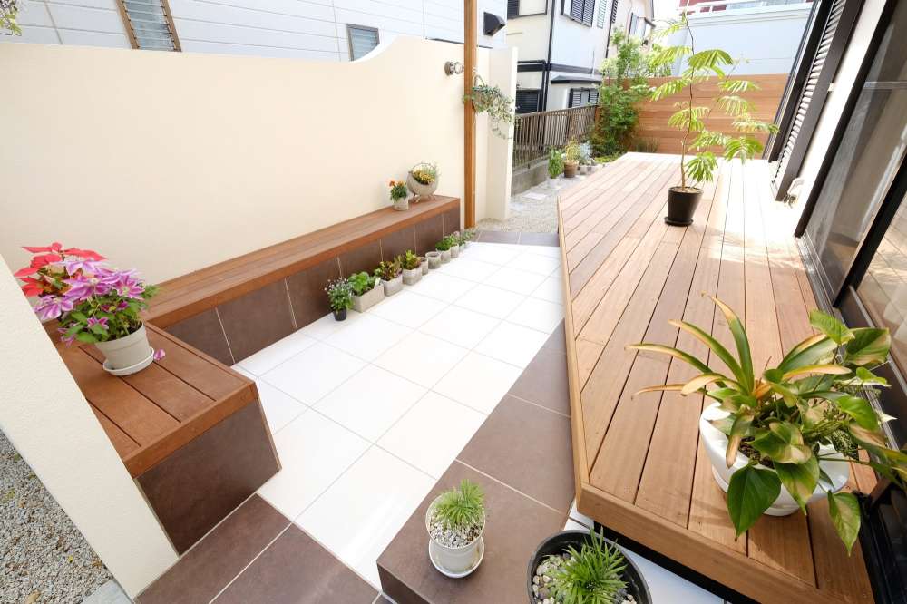 塗り壁に囲われたタイルテラスとウッドデッキ