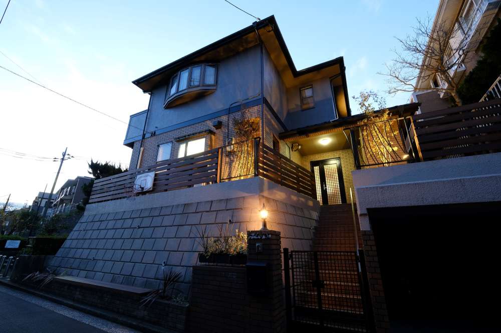 門灯の光に照らされた家の外観とフェンス