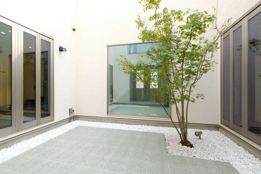 白砕石に囲まれた中庭のタイルテラスとモミジ