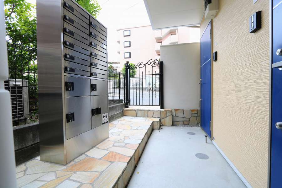 アプローチはイエロー系の石張り・ポスト宅配ボックス