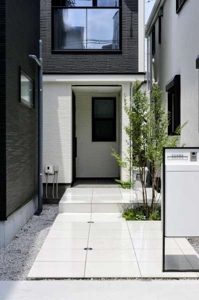 白い大判タイルを採用したアプローチ、スマート宅配ポスト、グラウンドライト。