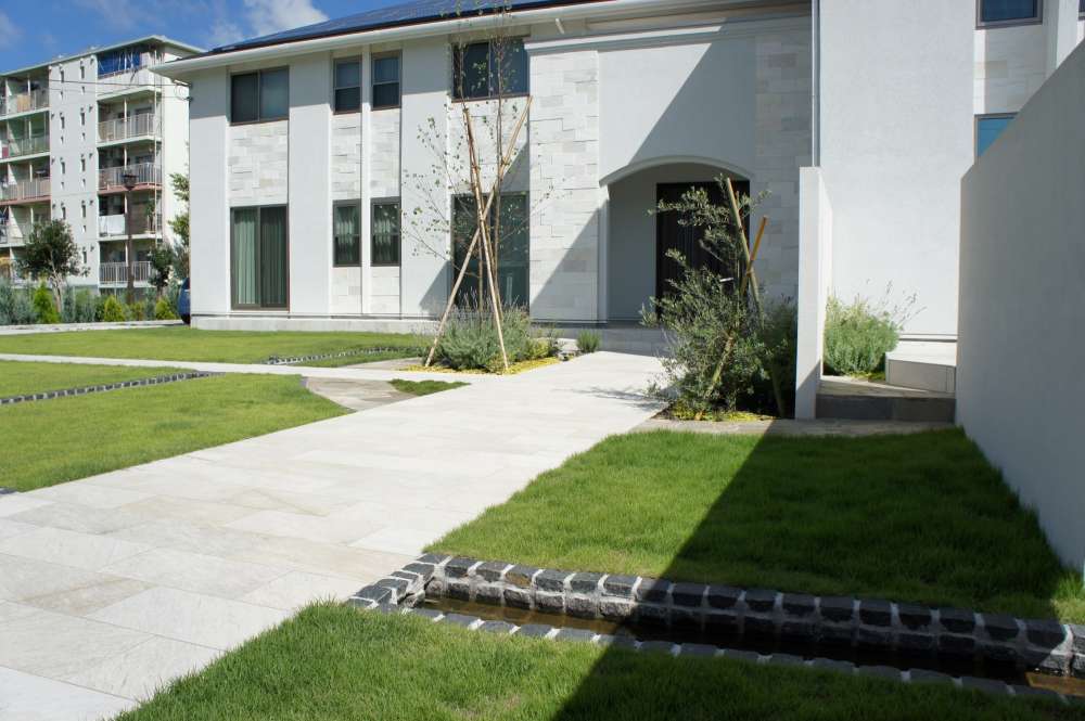 真っ白な外構に芝生と小川を